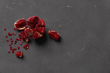 Siyah arka planda tohumları olan taze nar parçaları.