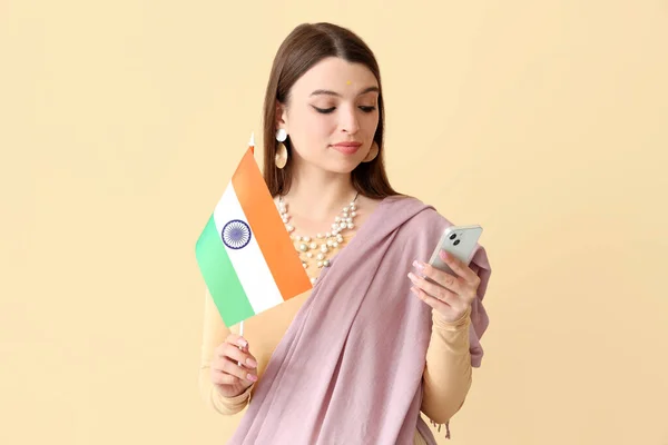 Junge Frau Mit Indianerfahne Und Handy Auf Beigem Hintergrund — Stockfoto