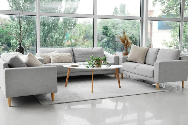 Modaya uygun gri koltukları, masası ve penceresi olan aydınlık oturma odasının içinde.