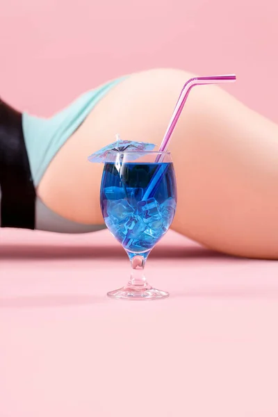 漂亮的性感女人 身穿泳衣 粉色背景的蓝色泻湖鸡尾酒 — 图库照片