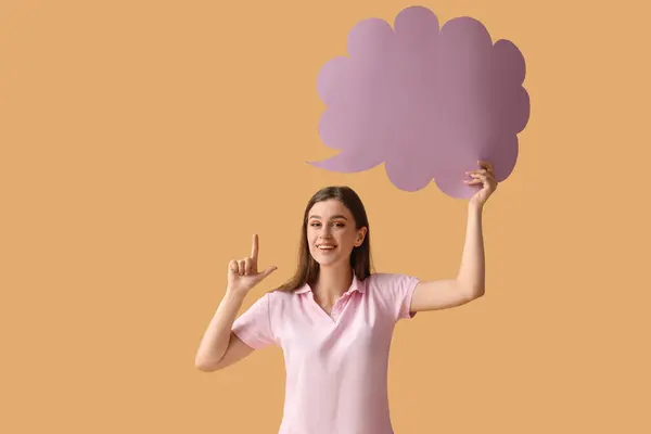 Beautiful happy young woman with speech bubble pointing at something on orange background