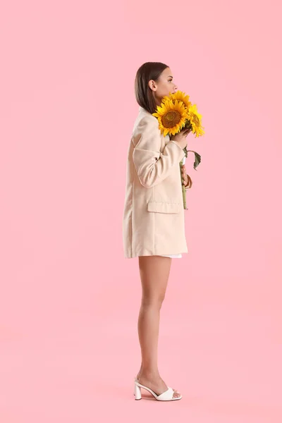 有一束粉色背景的美丽向日葵的年轻女子 — 图库照片