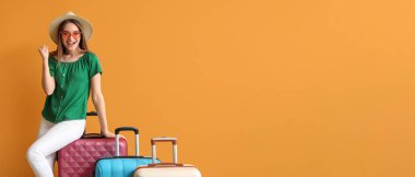 Turuncu arka planda bavulları olan mutlu genç bir kadın ve mesaj için yeri var.