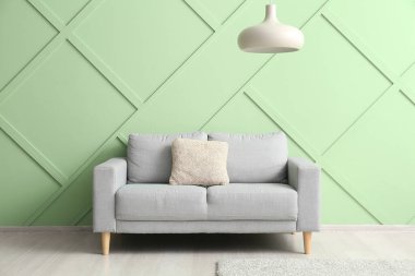 Stylish grey sofa near green wall