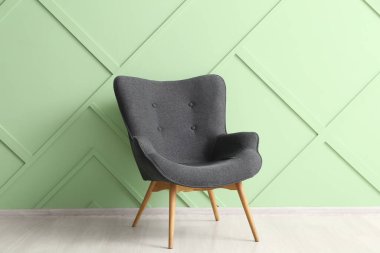 Yeşil duvarın yanındaki modern gri koltuk