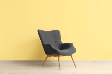 Modern grey armchair near yellow wall