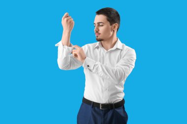 Genç iş adamı açık mavi arka planda kolunu kıvırıyor.