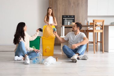 Mutfakta çöpleri geri dönüşüm kutularıyla sıralayan aile.