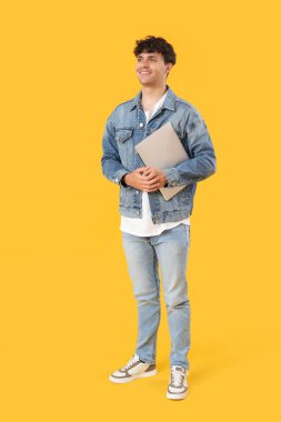 Sarı arka planda dizüstü bilgisayarı olan erkek programcı