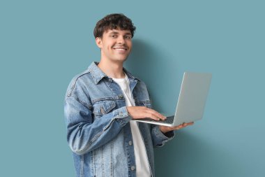 Mavi arka planda dizüstü bilgisayarla çalışan erkek programcı