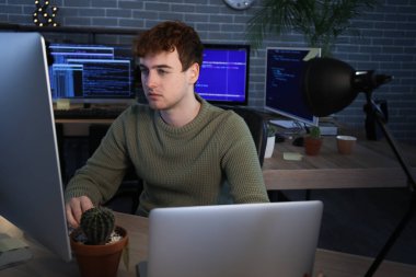 Erkek programcı geceleri ofiste bilgisayarla çalışıyor.