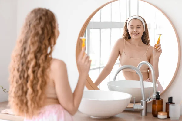 浴室里的年轻女人带着剃须刀靠近镜子 — 图库照片