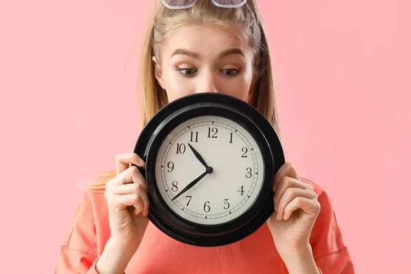 Young woman with clock on pink background, closeup. Deadline concept