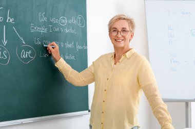 Sınıfta tahtaya İngilizce yazan kadın öğretmen.