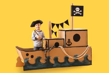 Sarı arka planda karton gemide dürbünle oynayan sevimli küçük bir korsan.