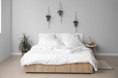 Çift kişilik yataklı, beyaz yastıklı ve çiçekli hafif yatak odasının içi.