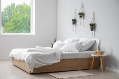 Çift kişilik yataklı, beyaz yastıklı ve çiçekli hafif yatak odasının içi.