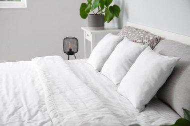 Modern yatak odasında beyaz yastıklı ve çiçekli rahat bir çift kişilik yatak.