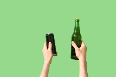 Yeşil arka planda şişe ve bira kutusu olan bir adam.
