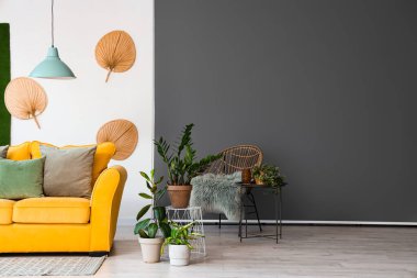 Sarı kanepeli ve çiçekli aydınlık oturma odasının içi.