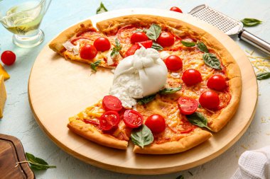Arkaplanda Burrata peyniri olan ahşap bir pizza tahtası