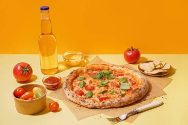 Lezzetli pizzalı kâğıt ve sarı arka planda patates cipsi.