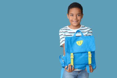 Mavi arka planda okul çantası olan küçük Afro-Amerikalı çocuk.