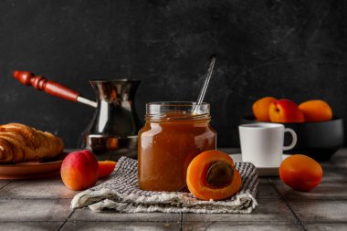 Kayısı reçelli kavanoz ve gri fayansta bir fincan kahve.