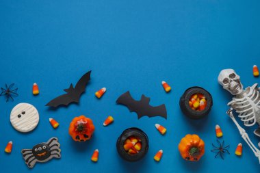 Lezzetli mısır, kurabiye, iskelet ve mavi arka planda Cadılar Bayramı dekoru olan kompozisyon