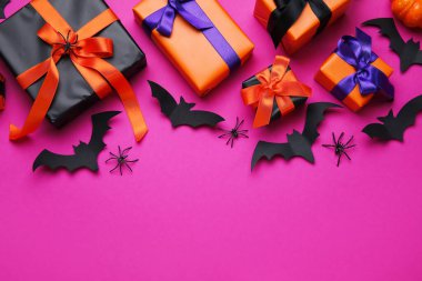 Pembe arka planda Cadılar Bayramı için hediye kutuları, örümcekler ve kağıt yarasalarla kompozisyon