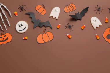 Lezzetli mısır, kurabiye, iskelet el ve kahverengi arka planda Cadılar Bayramı dekoru olan kompozisyon