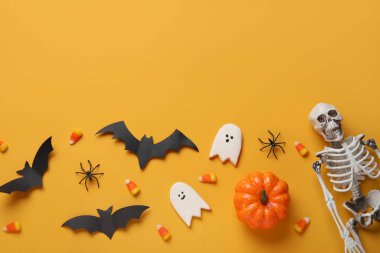 Lezzetli mısır, kurabiye, iskelet ve turuncu arka planda Cadılar Bayramı dekoru olan kompozisyon