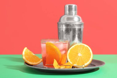 Bir bardak soğuk Negroni kokteyli, arkaplanda turuncu ve sallanan.