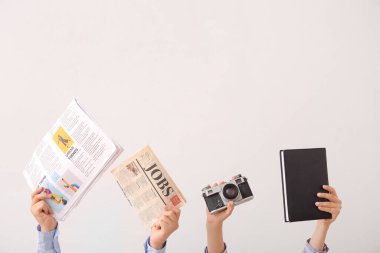 Gazeteli kadın eller, fotoğraf makinesi ve arka planda not defteri.