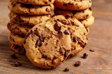 Tahta arka planda çikolata parçalı lezzetli kurabiyeler.