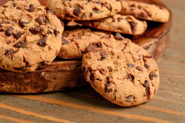 Tahta arka planda çikolata parçalı lezzetli kurabiyeler.