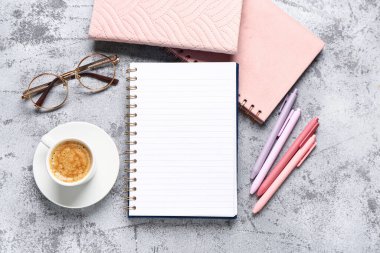 Gözlüklü defterler ve gri arka planda bir fincan lezzetli kahve.