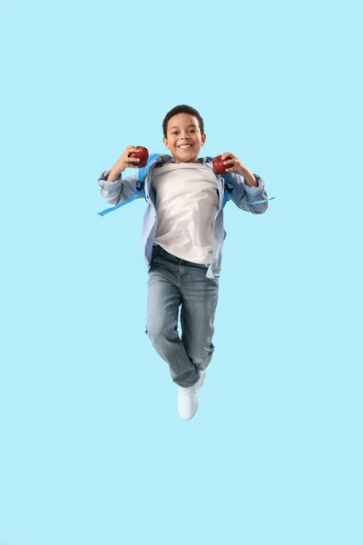 跳投着浅蓝色背景苹果的非洲裔小学生 — 图库照片