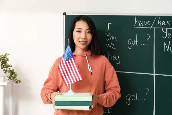 Female English teacher with USA flag and books in classroom