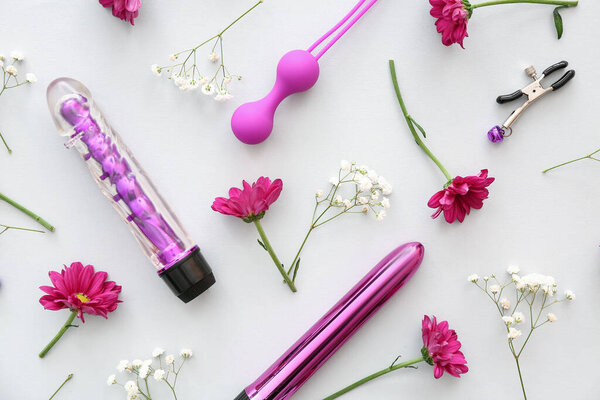 Состав с красивыми цветами, анальной вибрацией и вибраторами на белом фоне, крупным планом