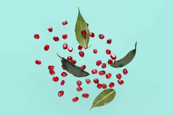 Fliegende Frische Granatapfelkerne Und Blätter Auf Türkisfarbenem Hintergrund — Stockfoto