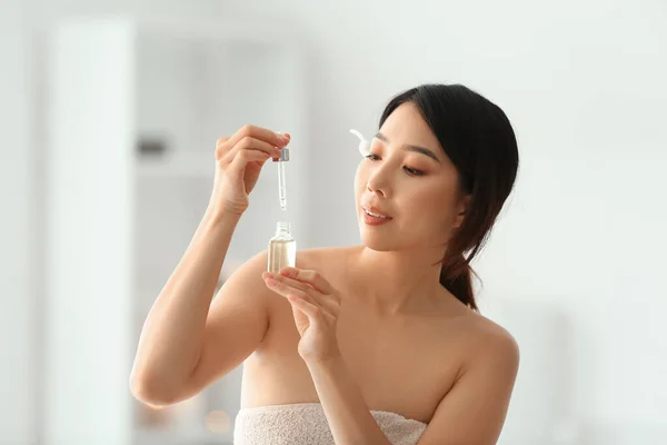 Pretty young Asian woman with essential oil in spa salon