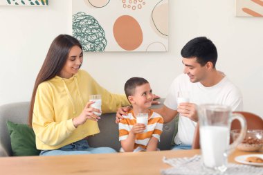 Ailesiyle birlikte evdeki kanepede süt içen küçük çocuk.