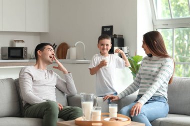 Little boy with his parents drinking milk at home clipart