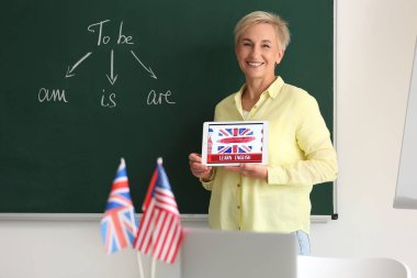 Sınıfta LeARN ENGLISH yazılı tablet bilgisayarlı kadın öğretmen