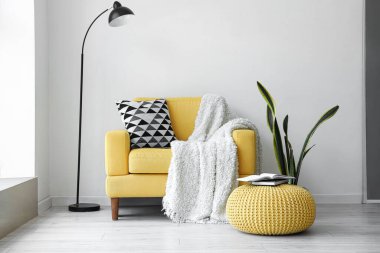 Oturma odasının içinde yastıklı ve ekoseli sarı koltuk