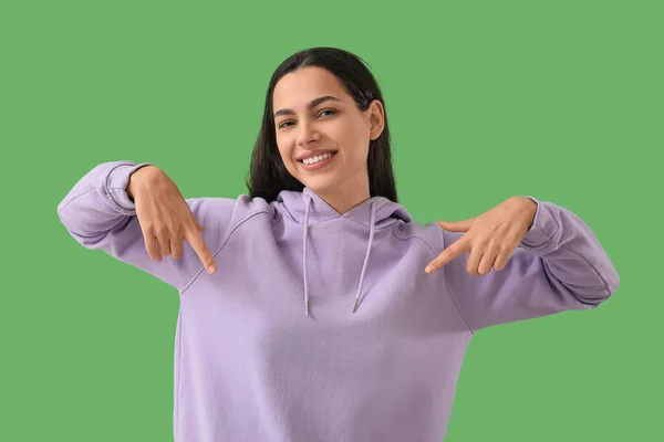 Piękna Młoda Kobieta Wskazująca Bluzę Zielonym Tle — Zdjęcie stockowe