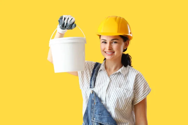 黄色の背景にペンキのバケツが付いている女性の装飾者 — ストック写真