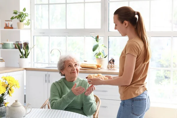 Young Woman Giving Tasty Croissants Her Grandmother Kitchen — Stock Photo, Image