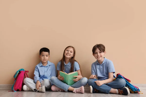 Маленькие Ученики Читают Книги Возле Бежевой Стены — стоковое фото